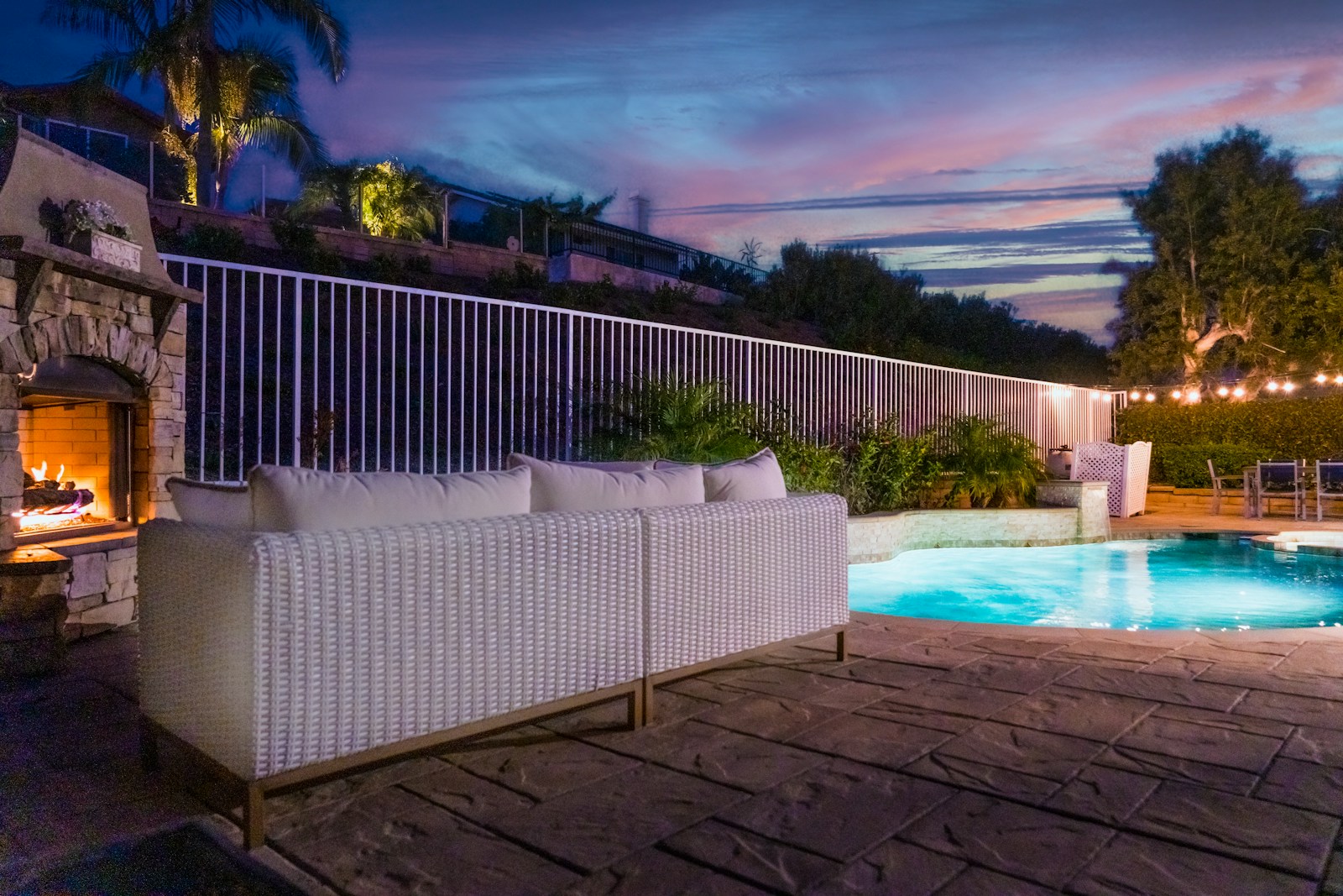 An outdoor fireplace heating a pool and deck area